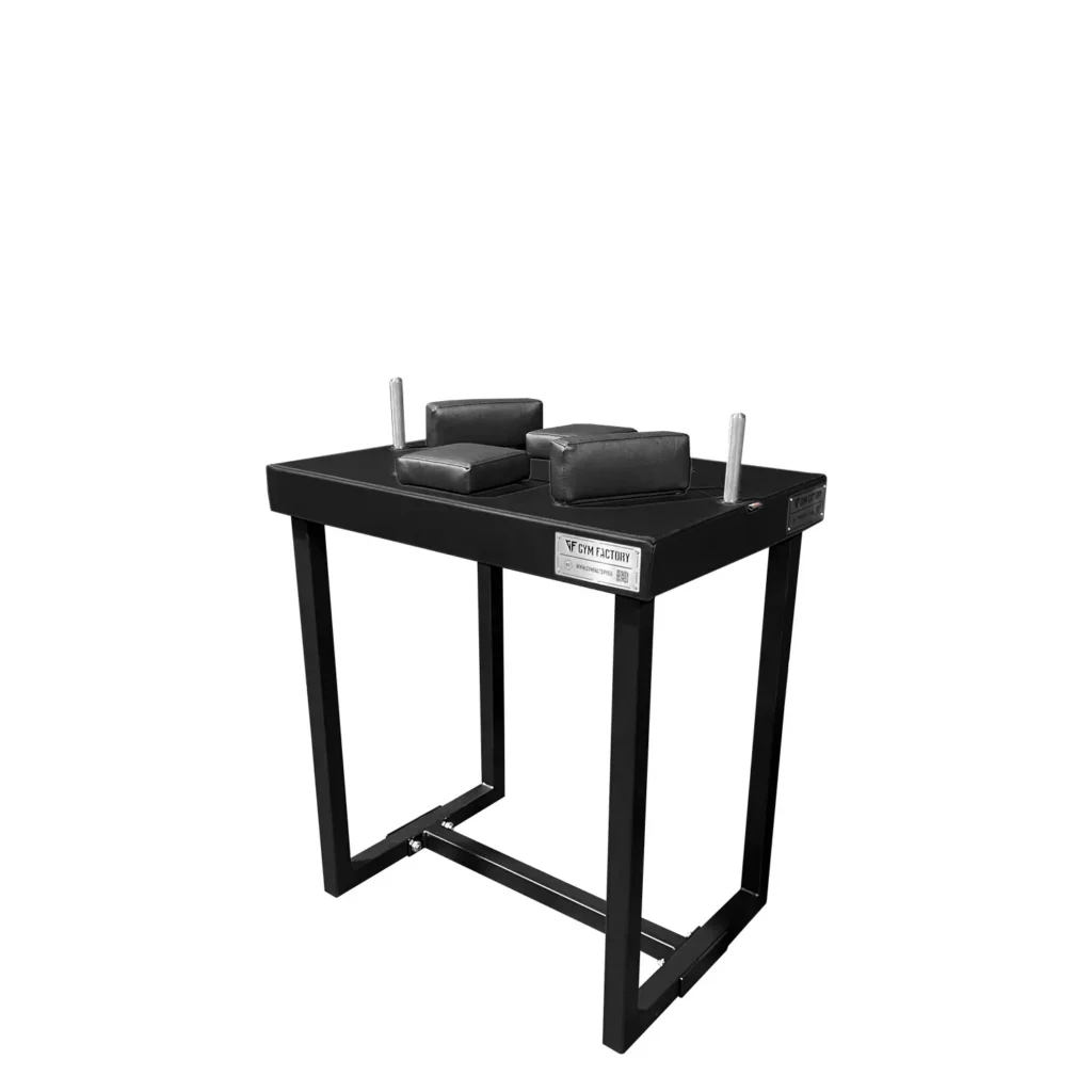 A sturdy strength training exercise equipment - an arm wrestling table with a red steel frame and black padded surface. The table features adjustable height settings, padded elbow supports, and grip handles for a secure and comfortable arm wrestling experience.